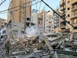 A man walks past debris at the site of an overnight Israeli airstrike in Beirut’s southern suburb of Bir al Abed on Tuesday.