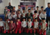 Taekwondo players posing along with organisers during a programme.