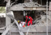 First responders searches a building that housed the offices of Doha-headquartered news network Al Araby TV following a missile strike in Tehran on Sunday.