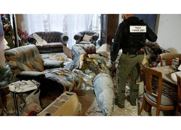 A member of the Israeli Police inspects part of an Iranian missile in a living room, after Tehran launches barrage of missiles towards Israel on Friday.