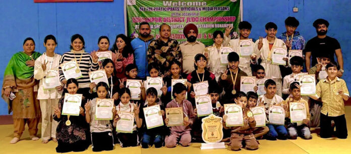 Judo players posing along with medals and certificates.