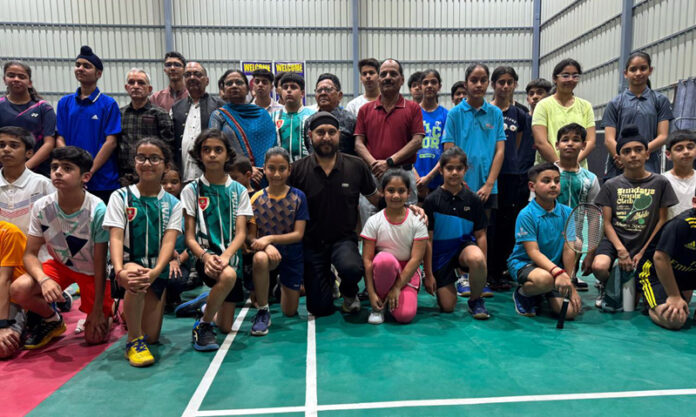Dignitaries posing along with young shuttlers during a programme.