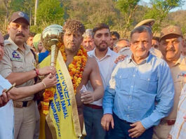 Wrestler posing along with dignitaries after winning the title.