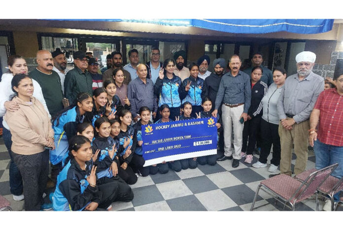 Sub-Junior Women's Hockey team posing along with cheque alongside dignitaries.
