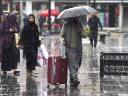 People walk with their umbrellas during rainfall in Srinagar on Friday. — Excelsior/Shakeel