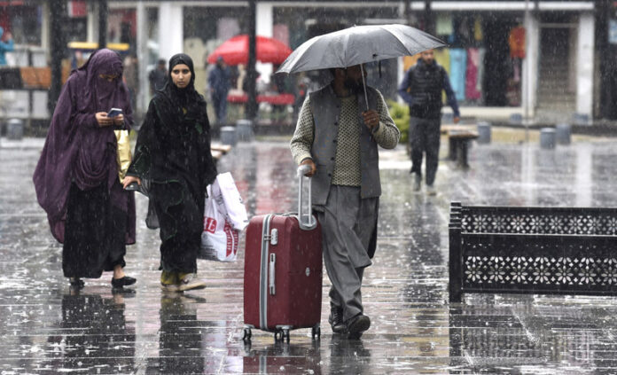 People walk with their umbrellas during rainfall in Srinagar on Friday. — Excelsior/Shakeel