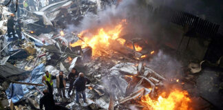 First responders and volunteers search through the rubble and burning cars at the site of an Israeli airstrike in Beirut, Lebanon on Wednesday.
