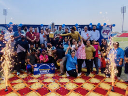 Winning team posing with the trophy alongside dignitaries during prize distribution ceremony.