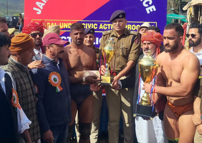 Dignitaries presenting trophy to winner wrestler during an event in Rajouri.