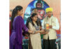 Dignitary presenting award to Shagun Saini during a programme.