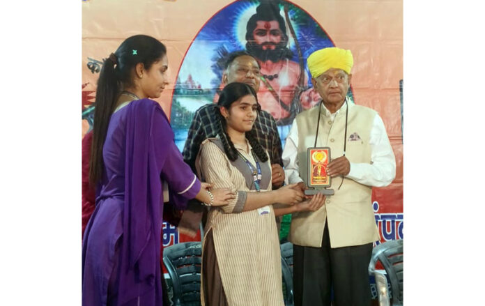Dignitary presenting award to Shagun Saini during a programme.