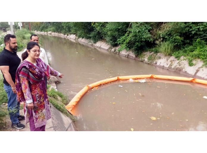 JMC officials pointing to a ‘Floating Trash Boom Barrier after installing it in a canal in Jammu on Tuesday.