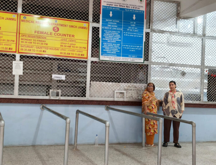 A mother and daughter waiting anxiously at the closed OPD registration counter of GMC Jammu, hoping for services to resume.