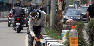 Workers paint road dividers near Civil Secretariat in Srinagar on Monday. -Excelsior/Shakeel