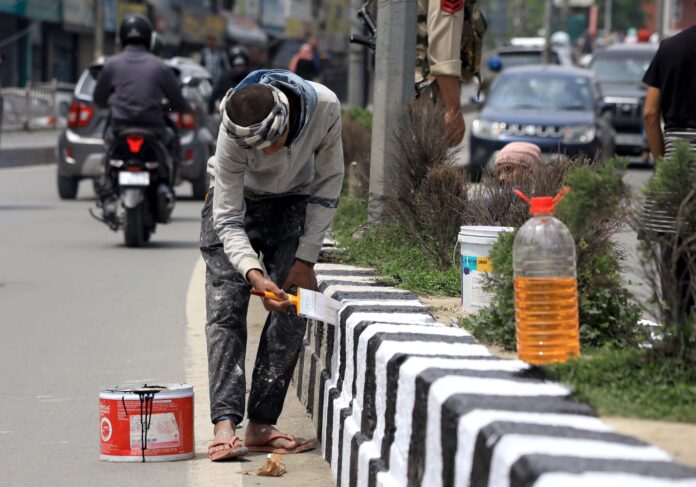 Workers paint road dividers near Civil Secretariat in Srinagar on Monday. -Excelsior/Shakeel