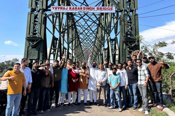 YRS members standing near Akhnoor bridge after installing the hoarding to display it as Yuvraj Karan Singh Bridge.
