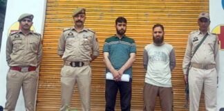 Cops and others standing outside a sealed medical shop in Ramban on Saturday. -Excelsior/ Parvez Mir
