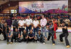 Dignitaries posing along with Wushu players during an event.