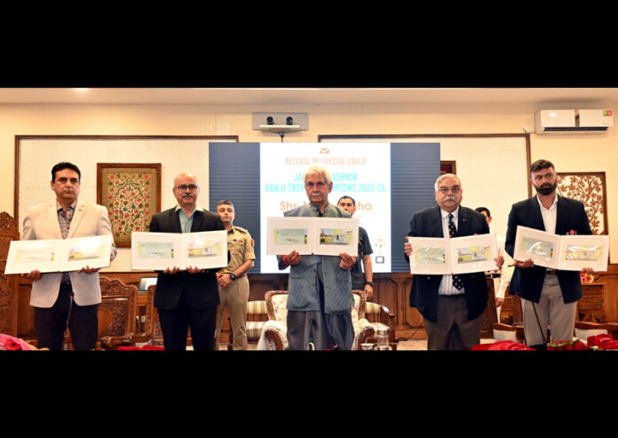 LG Manoj Sinha, along with dignitaries, posing with the Special Cover (postal envelope) released to commemorate J&K’s Ranji Trophy victory during a programme at Lok Bhawan.