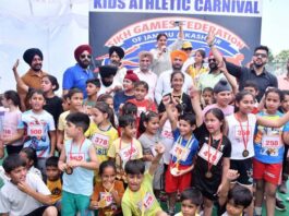 Dignitaries posing along with young athletes during a programme.