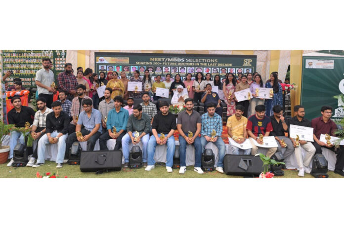 Dignitaries posing with meritorious students during the felicitation programme.