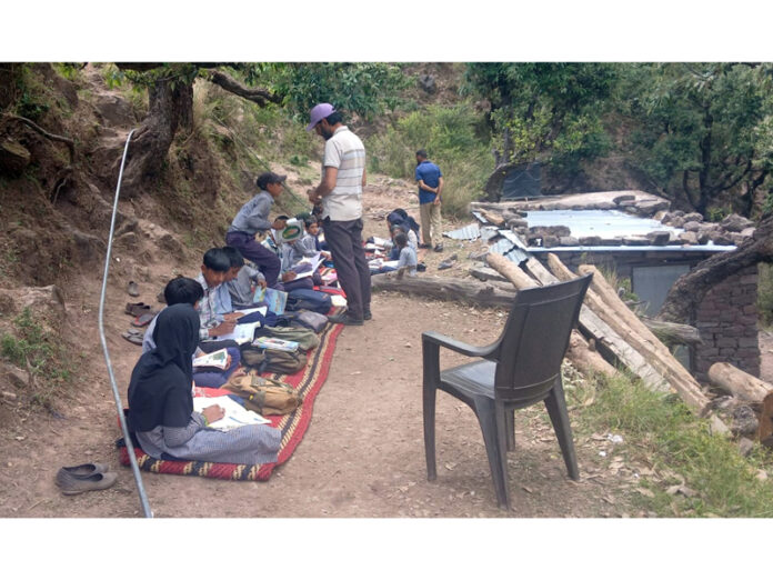 Students of Middle School Beena Kanthal in Rajouri district studying under the open sky.