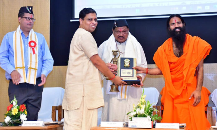 Swami Ramdev and Acharya Balkrishan of Patanjali Yogpeeth presenting a memento to Union Minister for Tribal Affairs, Jual Oram during an event in Haridwar on Thursday.