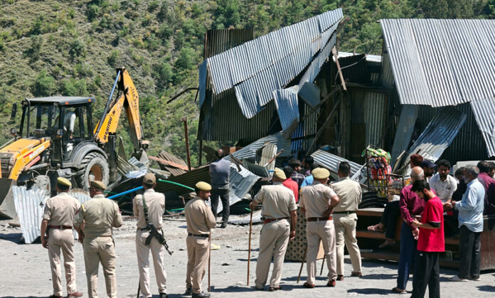 Cops standing in large number as authorities demolish a roadside eatery in Chanderkoot on Tuesday. -Excelsior/Parvaiz Mir