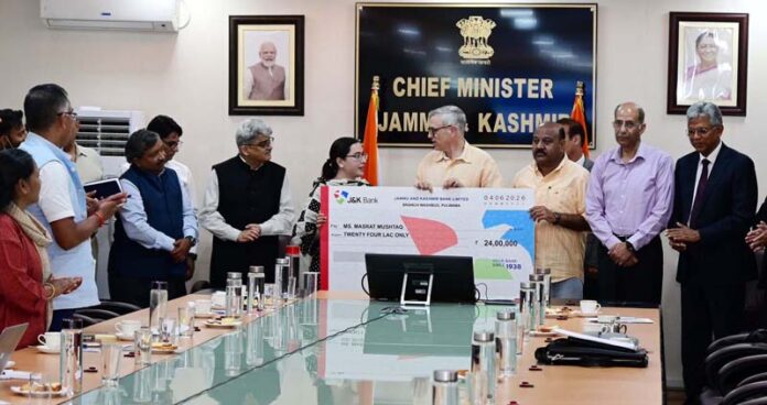 CM handing over cheque to a beneficiary of Mission YUVA at Srinagar on Thursday.